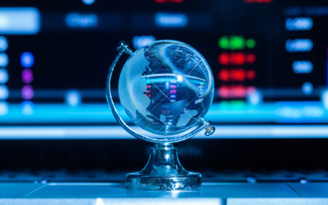 Crystal globe with stock information on the computer screen and dark blue background