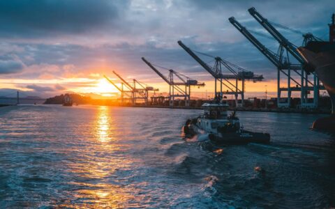 a panoramic shot of oil rigs at sea with a beautiful sunset in the background, under cloudy sky